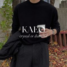 a man wearing a black kaeo crystal or diamond shirt holding a coffee cup in his hands