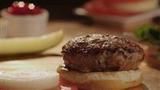 a hamburger sitting on top of a wooden table next to bananas and other food items