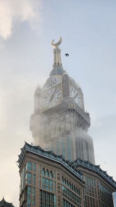 a tall building with a clock on it's side and birds flying in the air