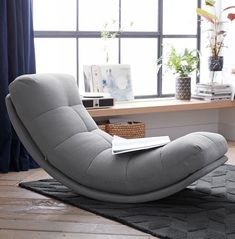 a living room with a gray chair and a book on the floor next to a window