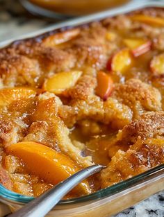 a casserole dish with peaches in it and a spoon next to it