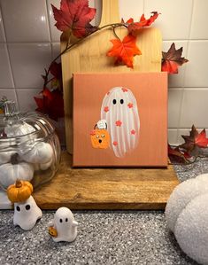 a wooden block with a painting on it next to some pumpkins and other decorations