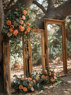 an old mirror is decorated with flowers and greenery in front of two mirrors on the ground