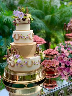 a three tiered wedding cake sitting on top of a table next to pink flowers