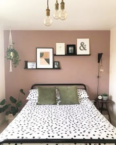 a bed with polka dot sheets and pillows in a small room next to pictures on the wall