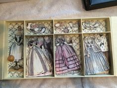 an open box with four paper dolls in it