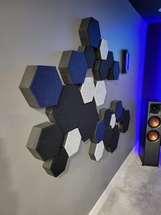 a room with speakers and a wall sculpture on the wall in front of it that looks like hexagonal shapes