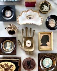 an assortment of antique items on display in a museum setting with framed pictures and hand - shaped objects