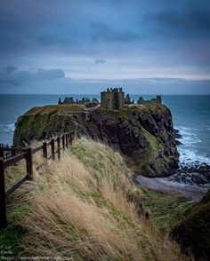 an old castle sitting on top of a cliff next to the ocean