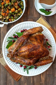 a roasted turkey on a white plate with cranberries and brussel sprouts