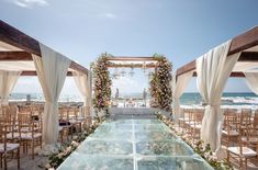 an outdoor ceremony setup with white draping and flowers on the aisle, overlooking the ocean