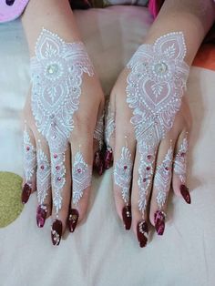 a woman's hands with white lace and red nail polishes on her fingers