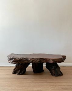 a wooden bench sitting on top of a hard wood floor next to a white wall