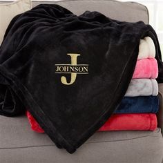 towels and blankets are stacked on top of a couch with the name j on them