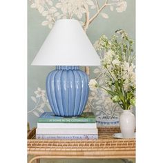 a blue lamp sitting on top of a table next to a vase with flowers in it