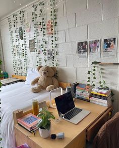 a laptop computer sitting on top of a wooden desk in front of a bed covered with plants