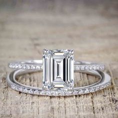 an emerald cut engagement ring on top of a wooden table