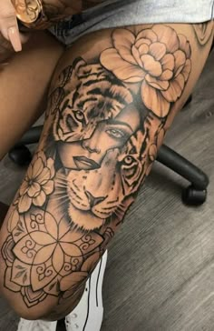 a woman's leg with a tiger and flower tattoo on her thigh, sitting next to a chair