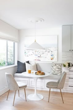 a dining room table with two chairs and a bowl of fruit on the plate next to it