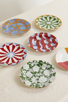 four plates with different designs on them sitting on a table top next to each other