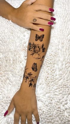 a woman's arm with flowers and butterflies tattooed on the left side of her hand