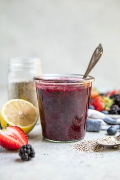 a glass jar filled with blueberry chia pudding next to sliced strawberries and lemon wedges