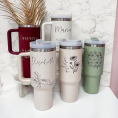 three different colored coffee mugs sitting next to each other on a white counter top