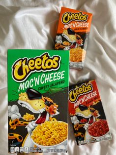 two boxes of cheetos macaroni and cheese cereal on a bed with white sheets