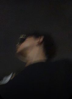 a blurry photo of a man in the dark with his head tilted to the side