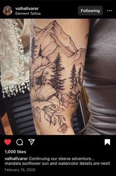 a woman's arm with mountains and trees tattooed on the back of her arm