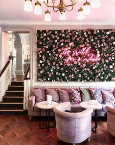 a living room filled with furniture next to a wall covered in pink and white flowers