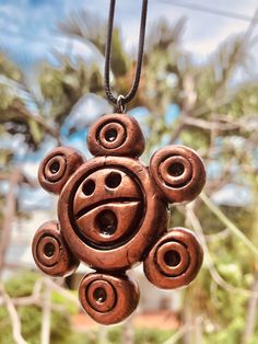 a brown necklace with an evil face hanging from it's center, surrounded by trees