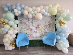 two blue chairs sitting in front of a balloon arch