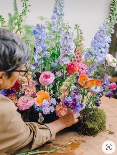 an older woman arranging flowers on a table