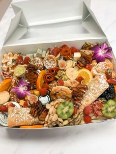 a white box filled with lots of different types of fruits and nuts on top of a table