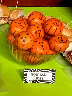 there is a bowl full of oranges with faces drawn on them, along with other food items