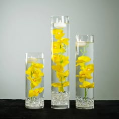 three tall vases with yellow flowers in them