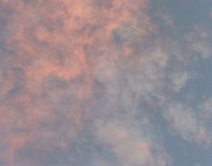 an airplane is flying in the sky with pink and blue clouds behind it on a sunny day