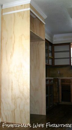 an empty kitchen with wooden cabinets and wood flooring on the walls, in front of a window