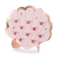 a pink and gold shell shaped broochle with stars on it's back