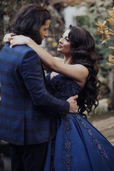 a woman in a blue dress hugging a man in a suit