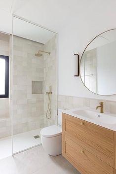 a bathroom with a sink, toilet and shower stall in the background is a large mirror