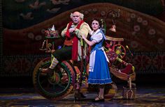 the man and woman are posing for a photo on stage with a horse drawn carriage