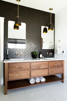 a bathroom vanity with two mirrors and lights above it, along with towels on the floor