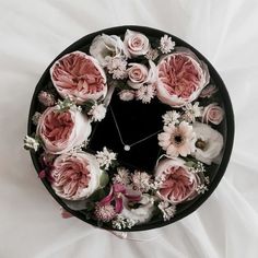 a black hat with pink and white flowers around it on a white sheeted surface