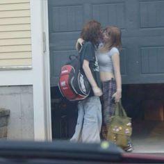 two young women standing in front of a garage door with their back to the camera