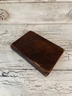 an old book sitting on top of a white wooden table next to a flower pot