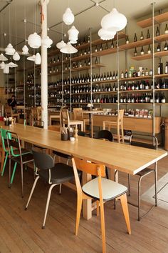 a long table with several chairs and bottles on the wall behind it in a restaurant