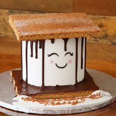 a cake shaped like a house with chocolate icing on top and eyes drawn on it