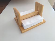 a napkin holder made out of wood and paper towels on top of each other, sitting on a white countertop